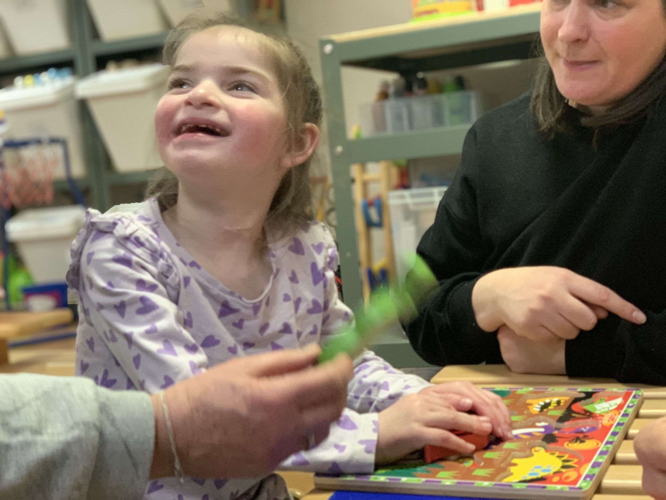 A young girl with Angelman's Syndrome solving a puzzle in her conductive education session.