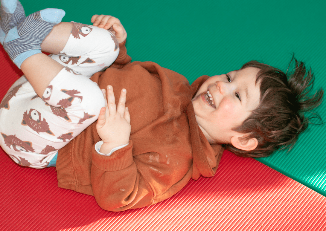 A young boy laying on the floor smiling.